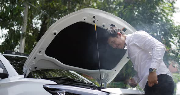 Portrait of Man open the hood and looking at car smoke engine