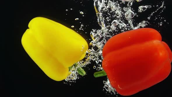 Two Ripe Peppers Falling Through Water