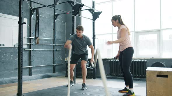 Active Guy Student Doing Ropes Battling Sports Exercise Training with Female Coach in Gym