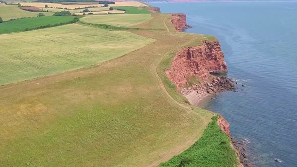 STATIC CROP Aerial, flying slow over red cliffs by a UK coastal town during summer holiday