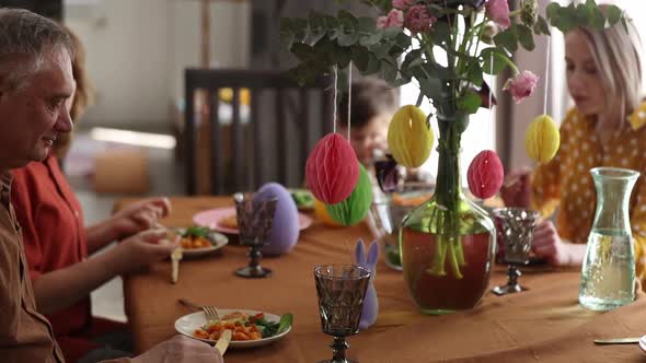 Family is eating at Easter dinner sitting at the table at home