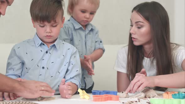 Young Happy Parents Showing Their Children How To Make Cookies