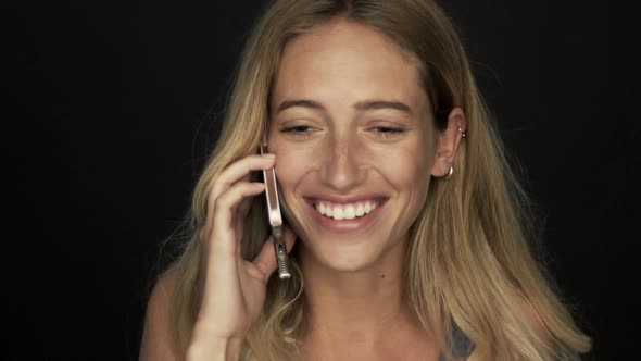 Young woman receiving good news and laughing while talking on cell phone