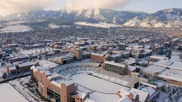 Aerial forward reveal of University of Colorado Boulder campus covered in snow on a winter morning w