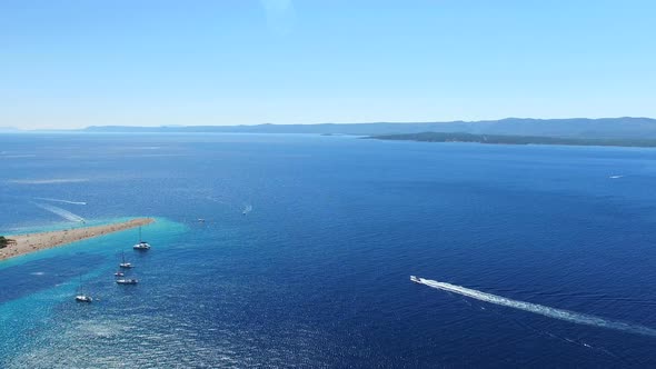 Motorboats passing the sandy beach Zlatni rat on the island of Brac, Croatia