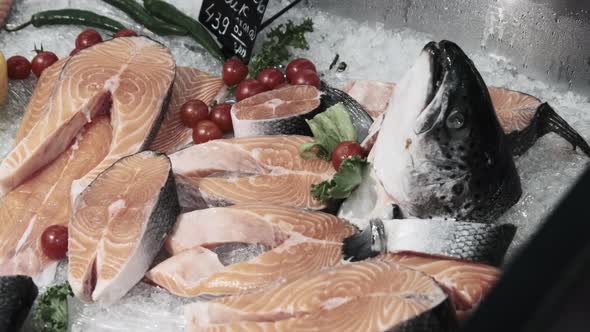 Composition of Trout and Salmon Steaks Lies on Ice in Showcase of Supermarket