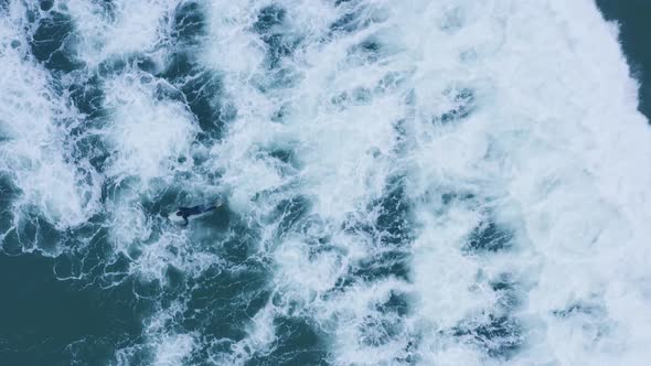 solo brave adventurous surfer moving against frothy sea waves, aerial