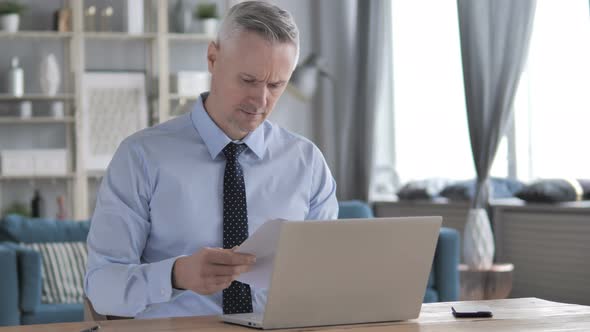 Senior Doctor Reading Medical Report in Clinic