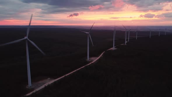 Wind Turbine Farm on Beautiful Purple Evening Mountain Landscape. Renewable Energy Production for