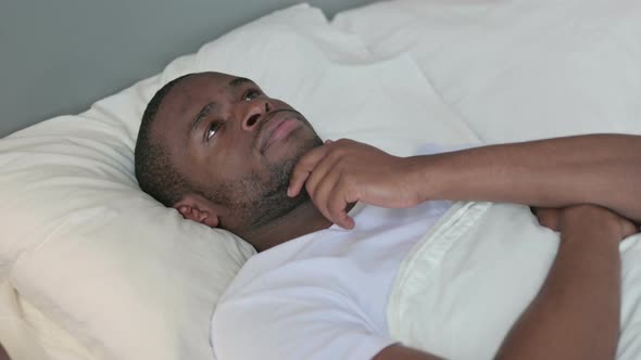 Pensive African Man Laying in Bed Thinking 