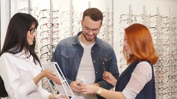 Red-haired Client Putting on Need Modern Glasses, Looking at the Mirror