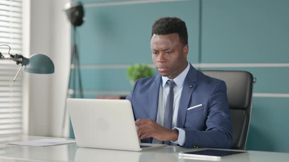 African Businessman Reacting to Loss While Using Laptop