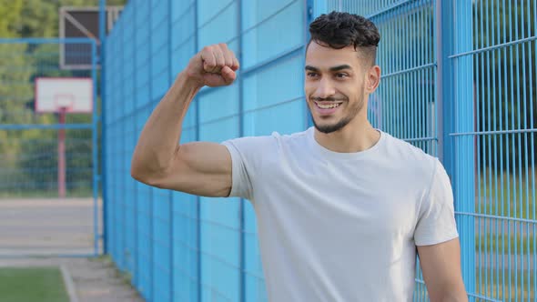 Satisfied Sincere Cheerful Arab Bearded Athletic Guy in Summer Sportswear Showing Off Muscles