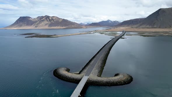 Western Iceland mountains by ocean With Sword shaped bridge over river
