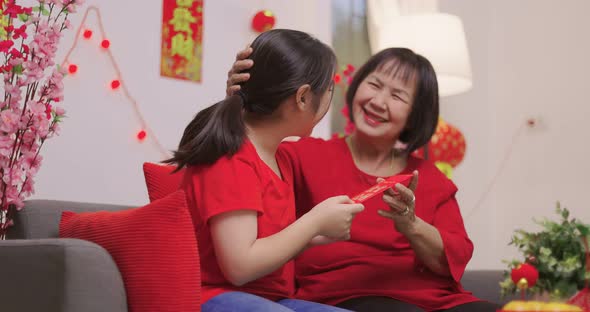 Happy Senior Asian Woman Giving Her Granddaughter A Lucky Red Envelope for Chinese New Year Gift.