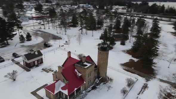 Rotating drone shot of Old Mackinac Point Lighthouse that rotates to show the Mackinac Bridge in Mac