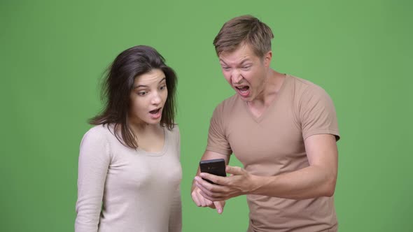 Young Happy Couple Using Phone While Looking Excited Together