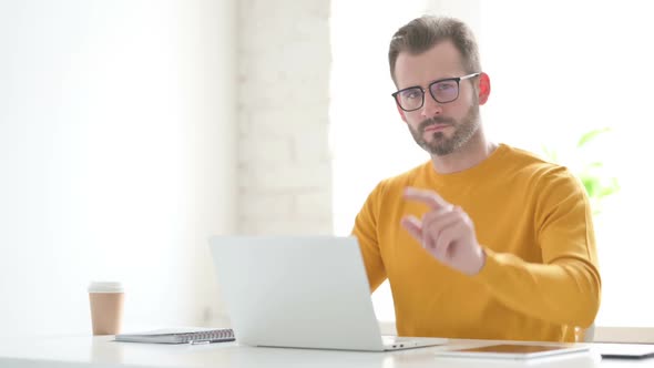 Man Pointing at Camera While Using Laptop in Office