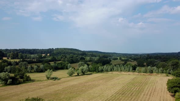 Drone shot flying over a farm and fields in Wilton, England in summer