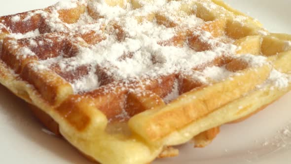 Preparation of waffles. Waffles are sprinkled with powdered sugar.