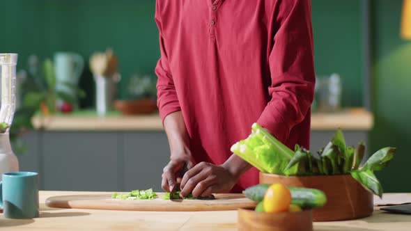 Afro-American Man Cutting Green Salad Leaves at Home