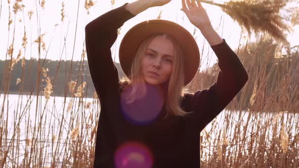 Caucasian Blonde Woman Waving Pampas Grass with Beige Hat in Black Sweater in the Countryside