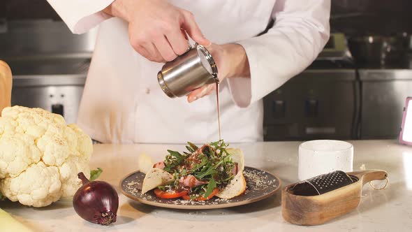 Chef Pouring or Sauce Over Salad Before Serving It To the Customer.