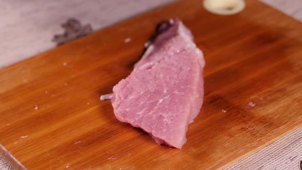 Pork Is on the Board. Sliced Pork Meat. Process of Chipping a Slice of Red Meat. Metal Hammer Falls