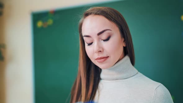 Portrait of a beautiful teacher. Lovely face of a young woman looking into a blue folder