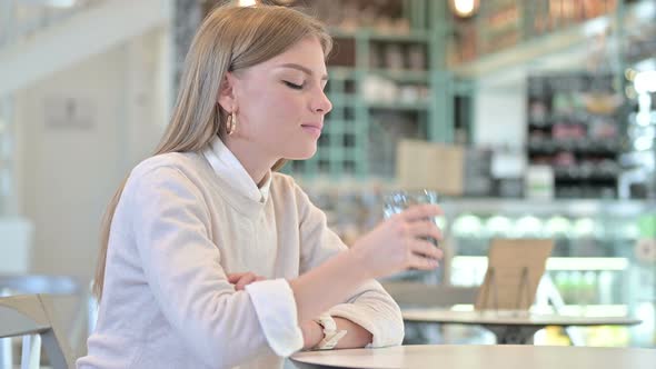 Healthy Young Woman Drinking Water in Cafe