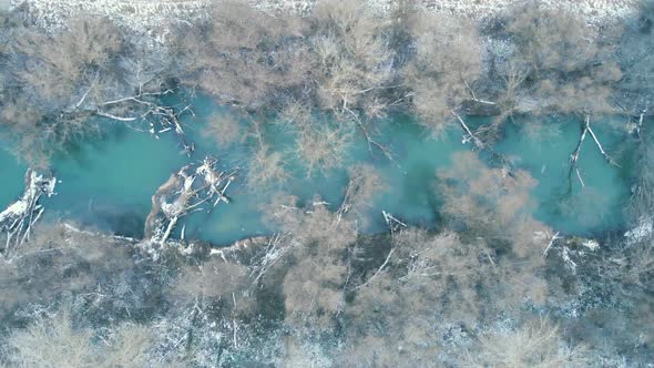 Flying over a beautiful landscape. Snow covered creek and park in the winter. Snowing