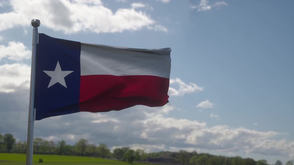 Texas Flag on a Flagpole Waving in the Wind Blue Sky Background