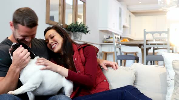 Happy couple playing with pug dog 