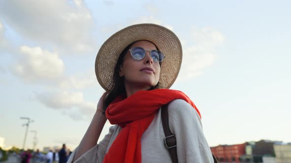 Happy woman with a red scarf on the embankment in summer