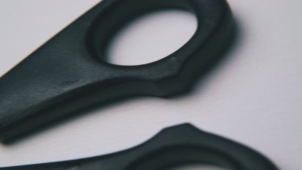 Scissors with Black Plastic Handles Lie on White Background