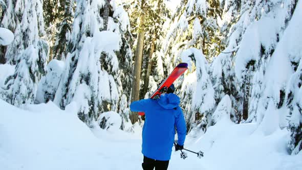 Rear view of person walking with snowboard and ski pole 4k