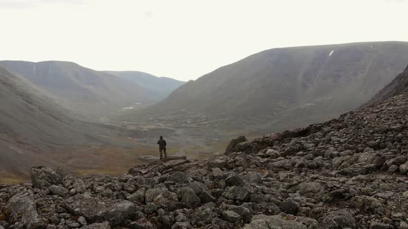 A Round Aerial View of a Picturesque Stone Valley with a Man Observing Mountains