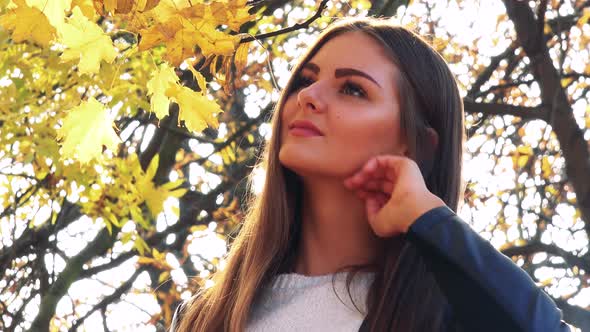 Young Beautiful Woman Smiles To Camera in the Park in Autumn Day - Closeup