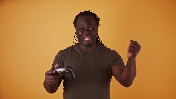 Excited African Man with Game Controler Isolated on Orange Background Happy As He Won the Game