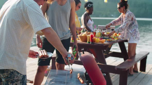 Friends Cooking BBQ Sausages on Lake Dinner Party