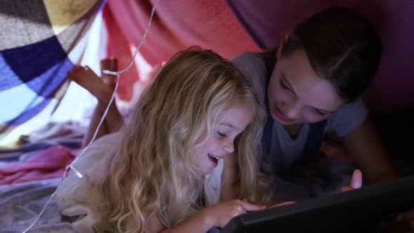 Sisters under sheets forming a tent