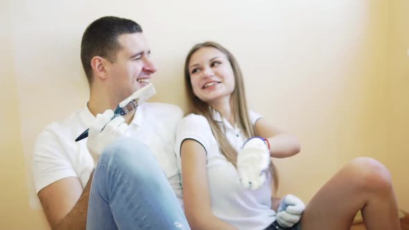 Young Couple Taking a Break From Renovating and Laughing Sitting on the Floor