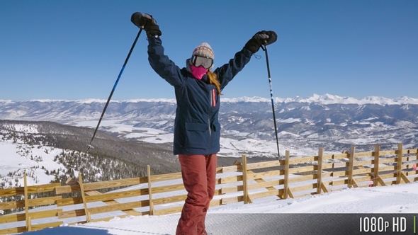 Happy Skier Cheering in Success at the top of a Ski Resort Mountain Range in Slow Motion