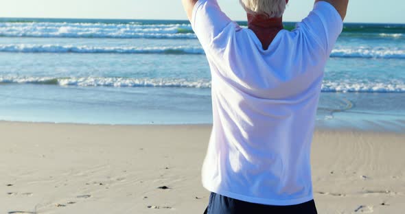 Senior man doing yoga on the beach