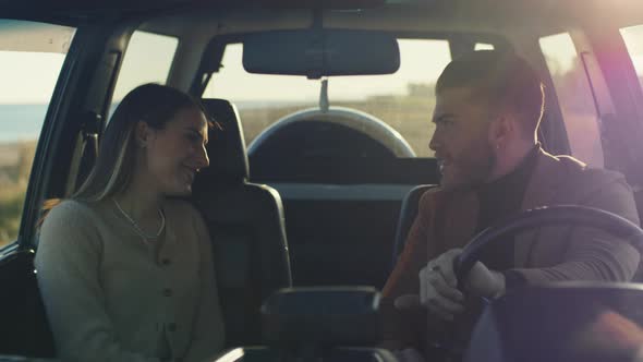 Couple jokes and laughs in the car at sunset