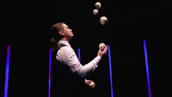 Orbital Shot Professional Circus Performer Juggling with Five White Balls Against a Black Studio