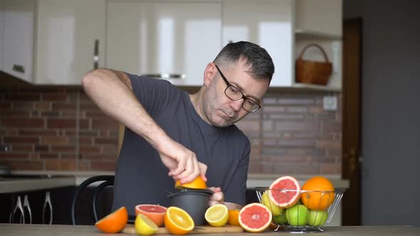 A Man Squeezes Orange Juice with Citrus Juicer