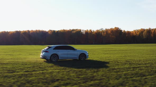 Vehicle Driving on Meadow Near Autumn Forest