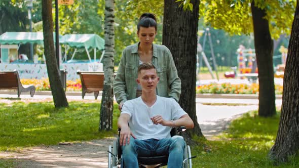 Friends Walking in Park a Man in a Wheelchair and His Female Friend Going in the Deserted Part of