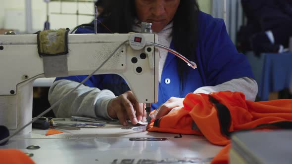 Mixed race woman using sewing machine in factory